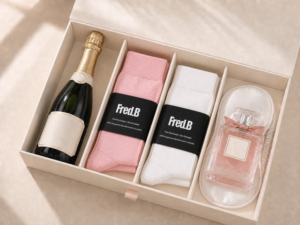 Fred.B corporate gift box with pink and white socks, champagne, perfume and a white silk eye mask